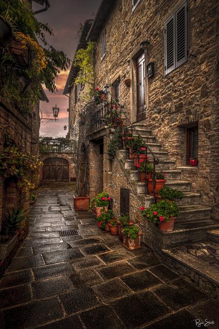Rustic stone alleyway with stairs, flower pots, and warm sunset light in Monticchiello, Tuscany — fine art photography print by Ryan Smith