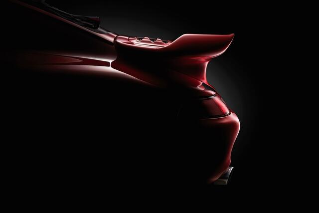 Close-up fine art photograph of the rear detail of a red 1985 Porsche 930 Turbo, with dramatic lighting emphasizing shape, curves, and reflections.