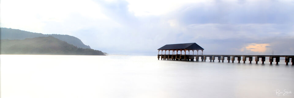 Calm, eerie morning at the Hanalei pier on Kauai as one person stands  on the pier. 