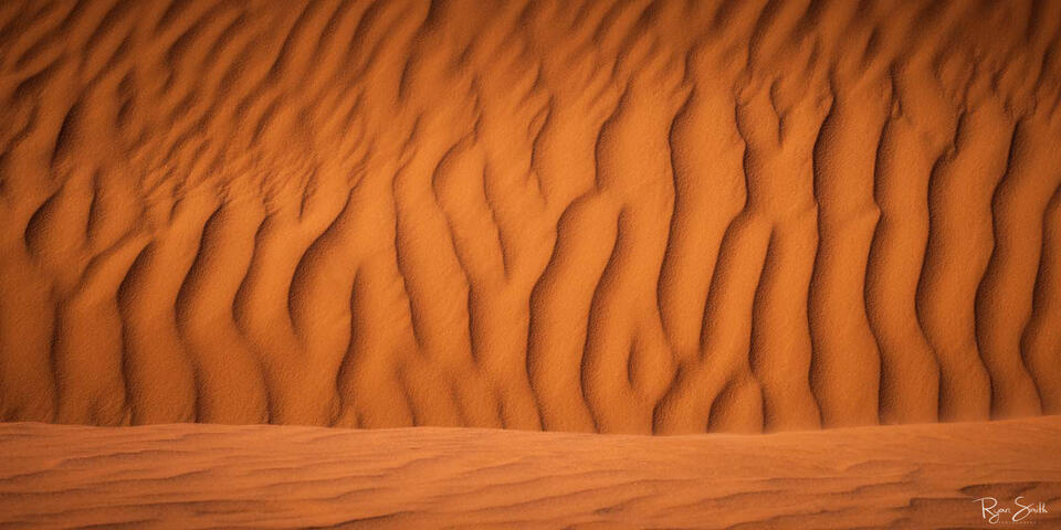 Desert sand up close creates an abstract wave pattern with beautiful shadows and light.
