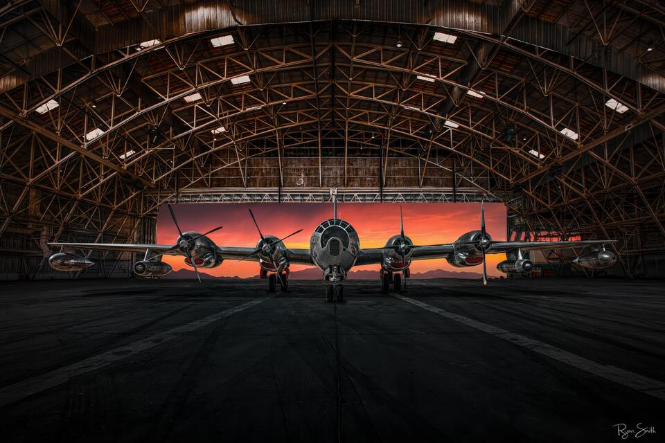 Historic Superfortress-era aircraft resting inside a large steel aircraft hangar at dusk, captured as a fine art aviation photograph by Ryan Smith.