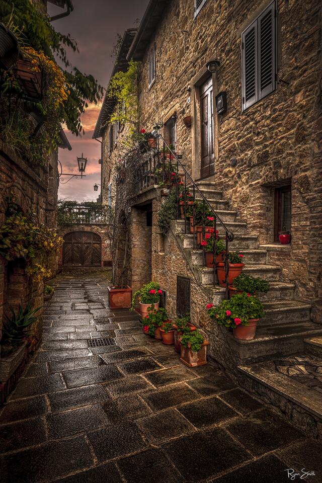 Rustic stone alleyway with stairs, flower pots, and warm sunset light in Monticchiello, Tuscany — fine art photography print by Ryan Smith