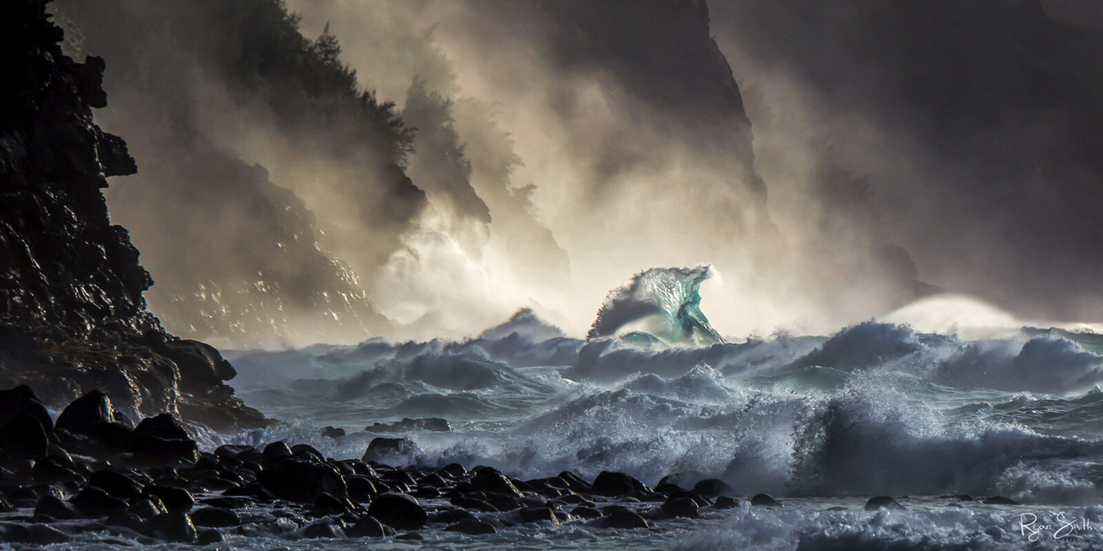 Waves crash into a rocky beach while mist and fog fill the air in this stormy scene with a panoramic aspect ratio.