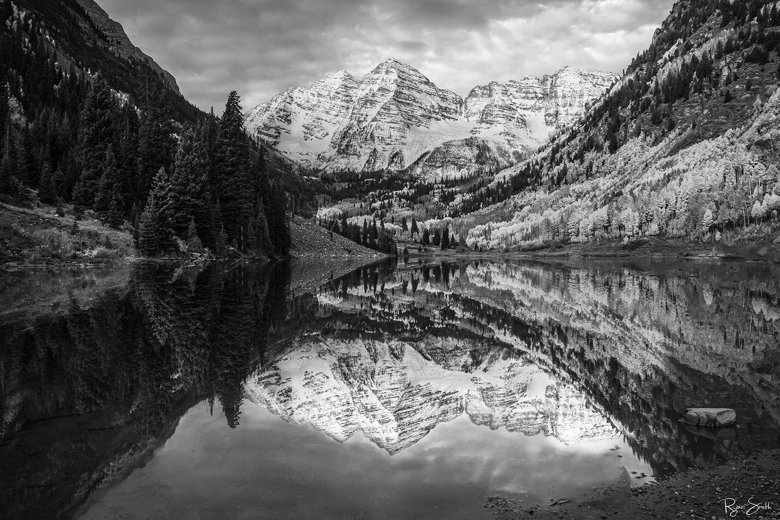 A beautiful sunrise at The Maroon Bells catches Snow covered Maroon Peak and North Maroon Peak reflecting in the lake surrounded...