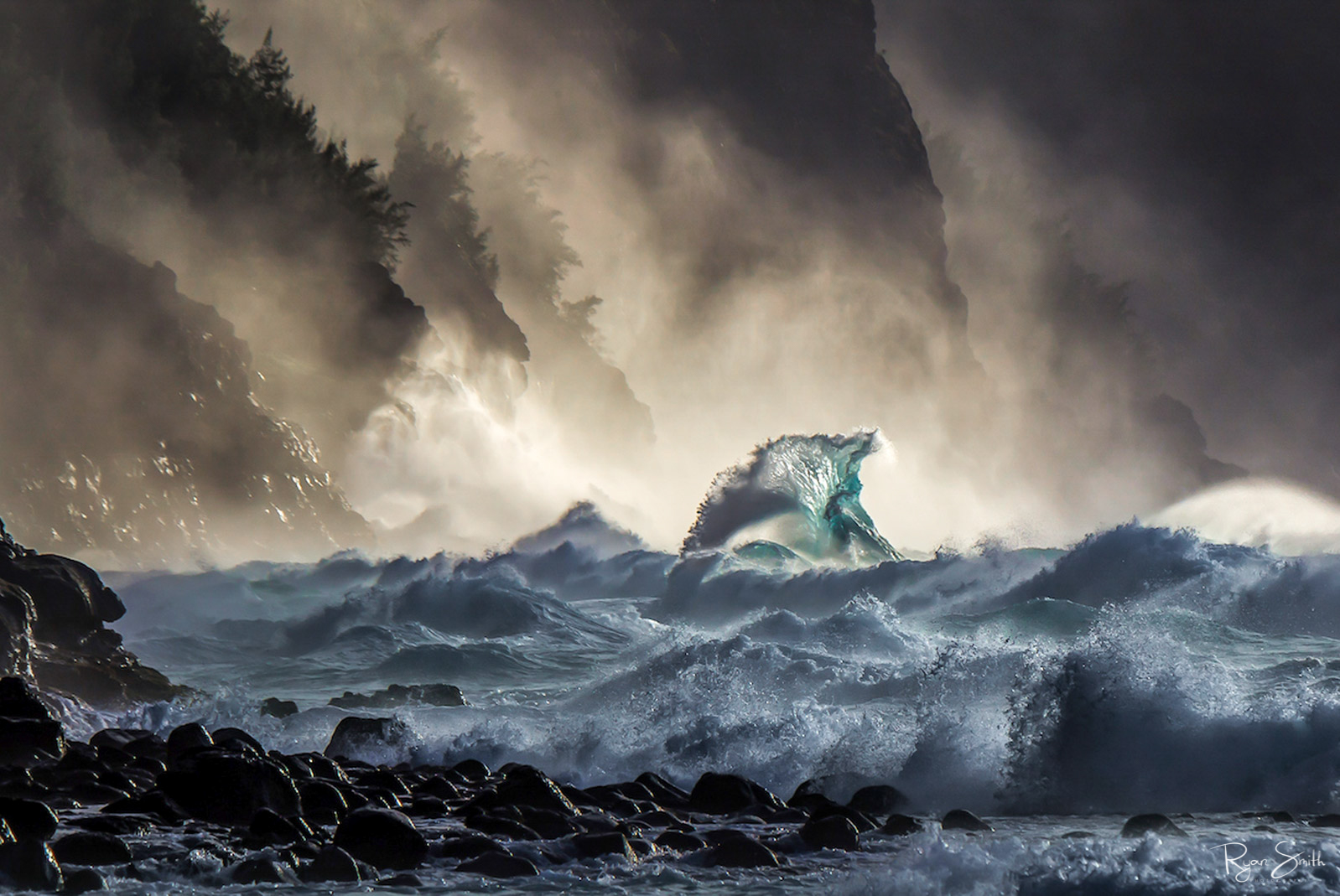 Waves crash into a rocky beach while mist and fog fill the air in this stormy scene.