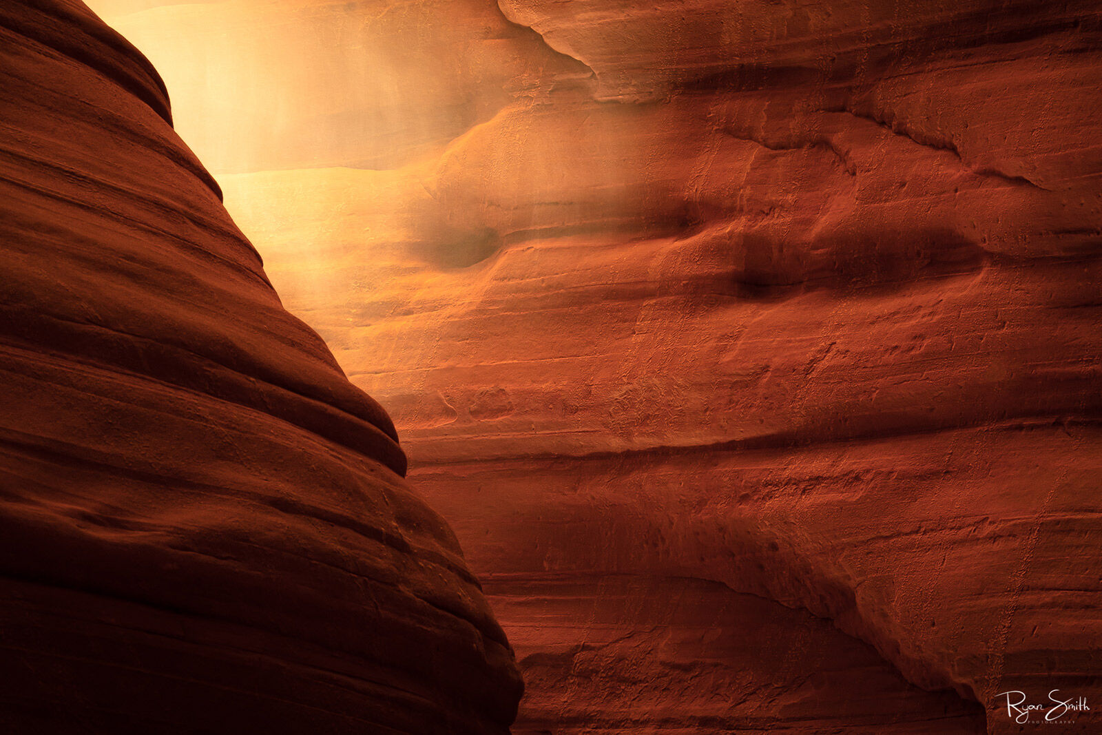 Inside a canyon, close to the orange-lit sandstone walls, the light shines in.